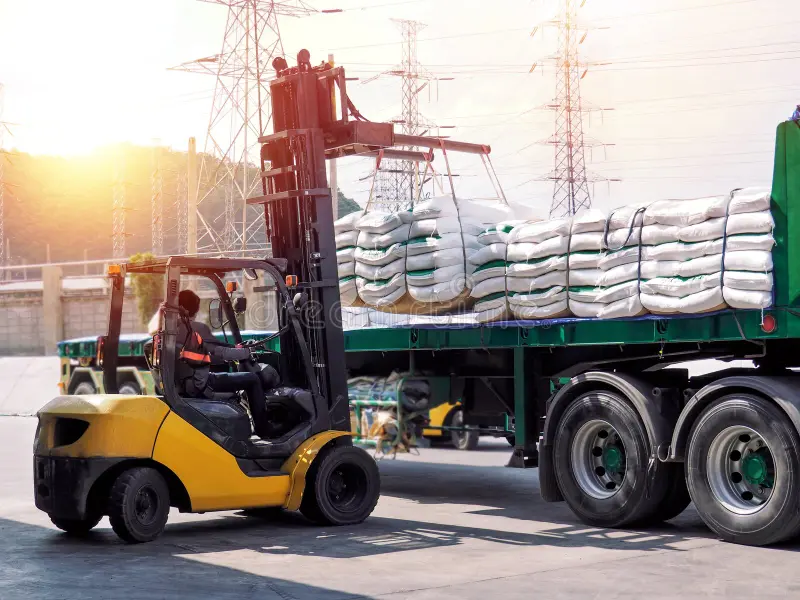 Large warehouse with workers packaging products and cargo trucks